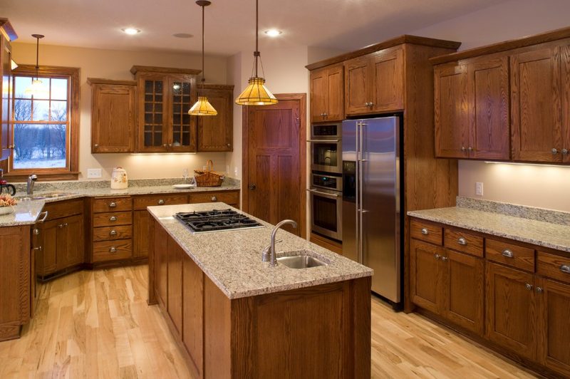 Cocina de madera con isla central y encimera de piedra en Ayamonte